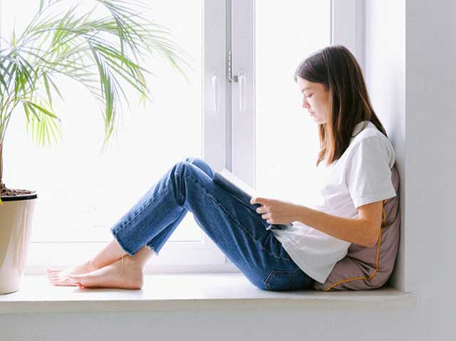 Woman with laptop sitting on a window ledge
