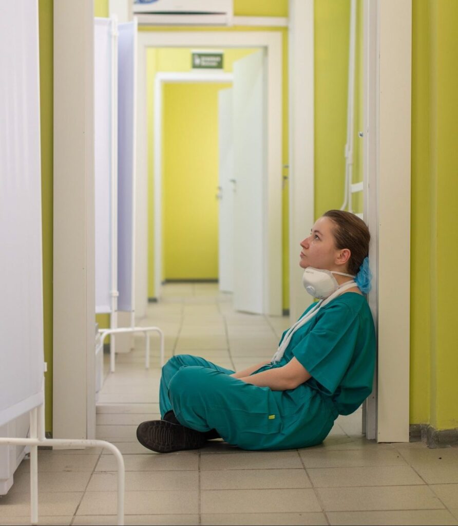 Exhausted female nurse sitting in a corridor