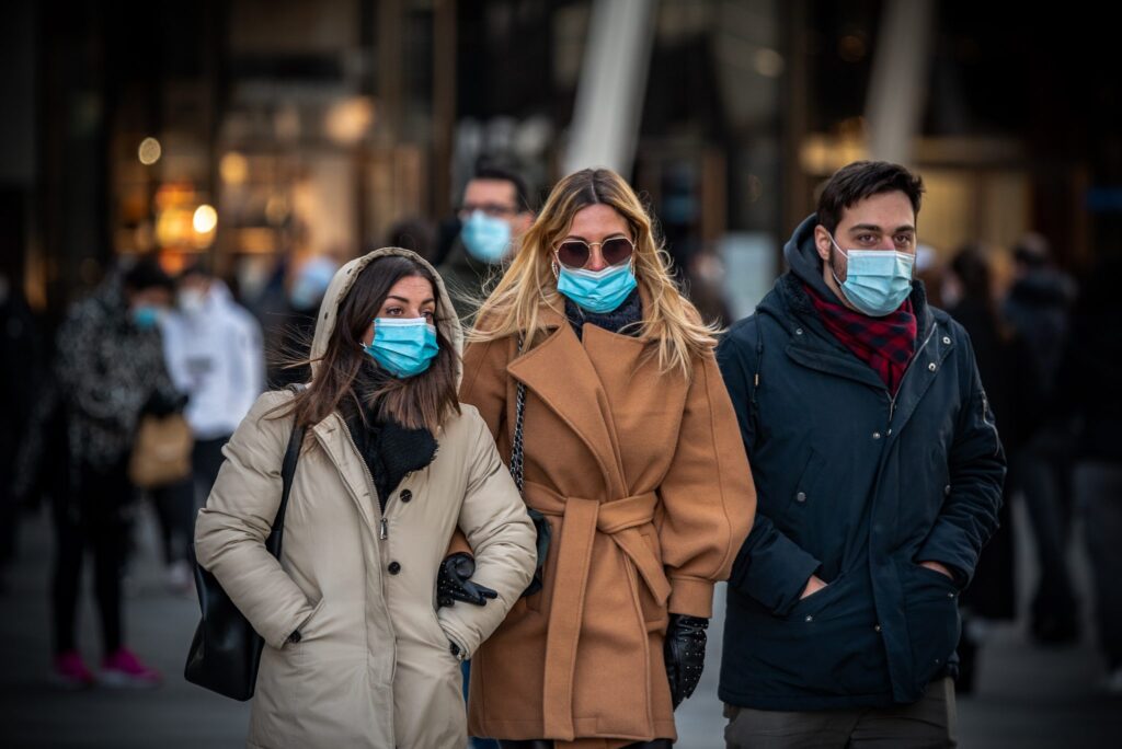 Three people outside wearing warm clothing and wearing face masks