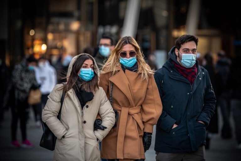 Three people outside wearing warm clothing and wearing face masks