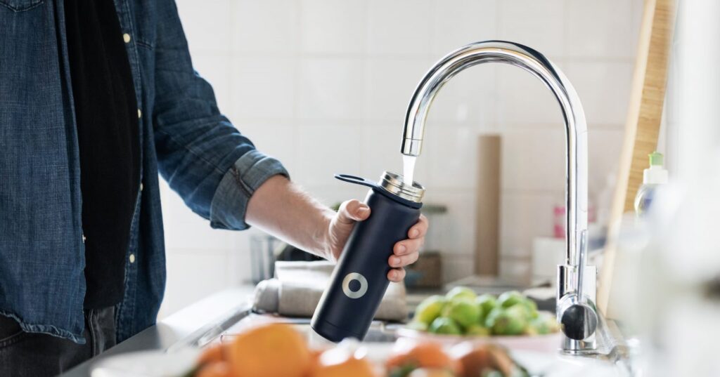 A man filling a water bottle from a tap