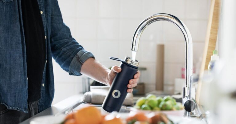 A man filling a water bottle from a tap