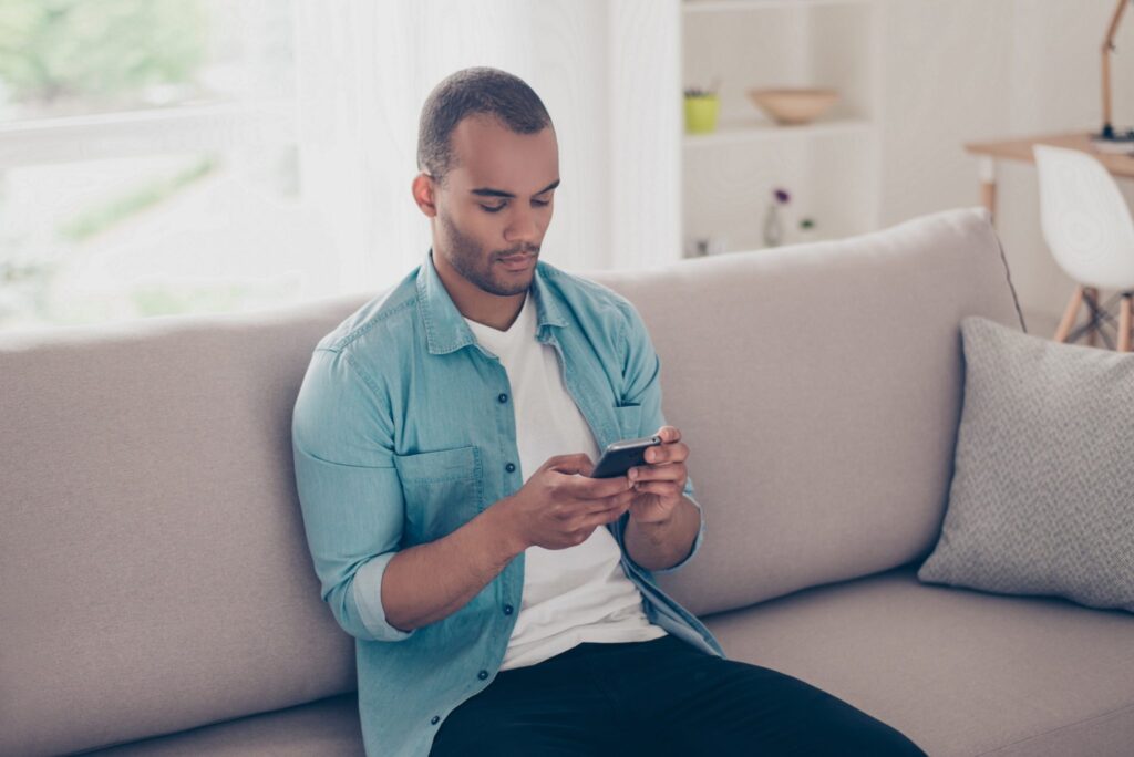 Man sitting on a sofa looking at a phone