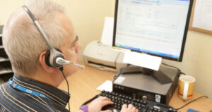 Man wearing a headset looking at a computer screen