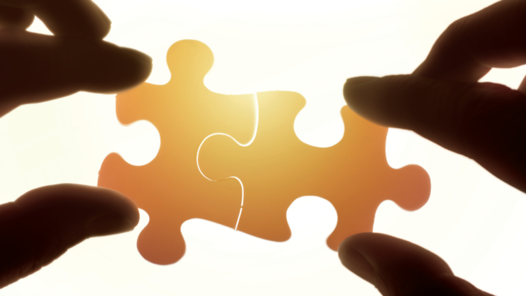 Two hands placing two jigsaw pieces together