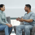 A woman and a man sitting opposite each other, the man is gesturing