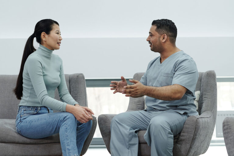 A woman and a man sitting opposite each other, the man is gesturing