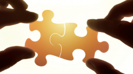 Two hands placing two jigsaw pieces together
